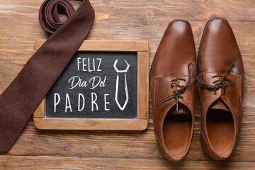 Greeting card for International Father's Day with male shoes and necktie on wooden background
