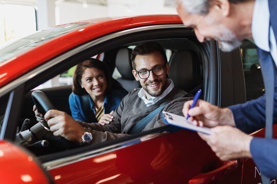 Beautiful young couple choosing a new car at car showroom.