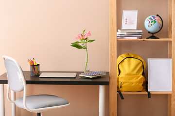 Stylish interior of modern room with backpack, globe and stationery