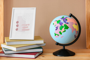 Stack of books, picture and globe on shelf, closeup