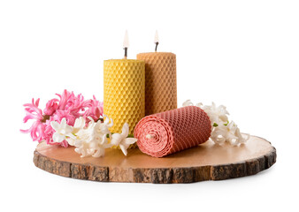 Obraz na płótnie Canvas Wooden board with wax candles and flowers on white background