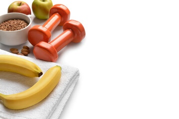 Dumbbells, towel and healthy products on white background, closeup