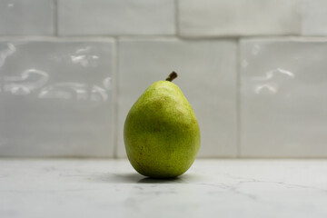 Green pear on white counter top