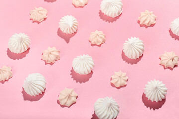 Many sweet meringue on pink background, closeup