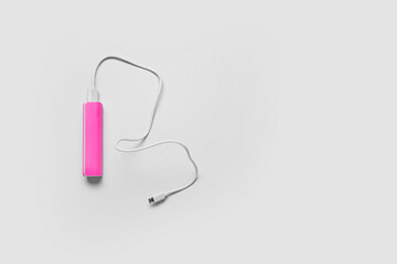 Pink power bank with USB cable on light background