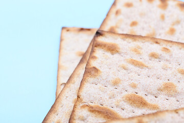 Jewish flatbread matza for Passover on blue background, closeup