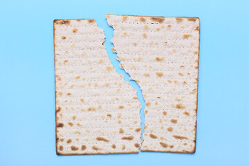 Torn Jewish flatbread matza for Passover on blue background
