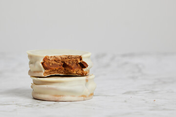 Argentinean white chocolate alfajores with dulce de leche on a marble table.