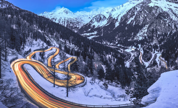 Long exposure with light trails of the Maloja Pass road in Engadin during blue hour in winter, Switzerland 