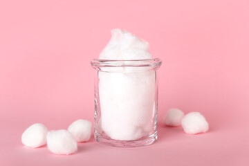 Glass jar with cotton wool on pink background