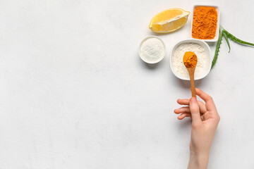 Woman making turmeric mask on light background