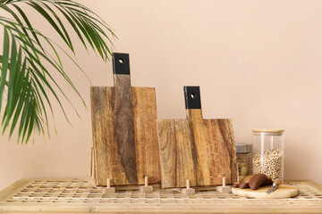 Wooden cutting boards, bread and jars with products on table near light wall