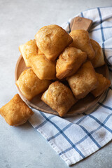 Freshly baked baursak on a wooden plate on a gray background. Traditional Kazakh baking.