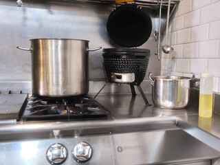 Large pot on the cooker of a restaurant next to oil and an electric fryer