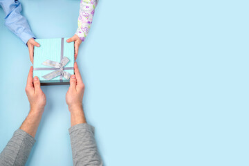 a father receives a gift box with a bow from the hands of his child in close-up