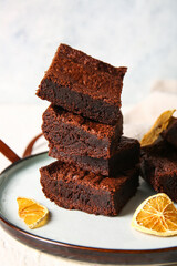 Plate with pieces of delicious chocolate brownie on light background