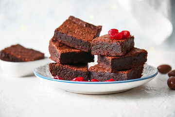 Plate with pieces of delicious chocolate brownie on light background
