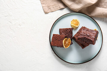 Plate with pieces of delicious chocolate brownie on light background