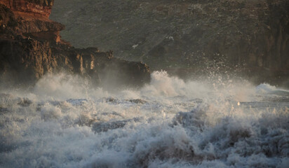 View of raging sea waves beating a rocky cliff at the coast on the mountain area background