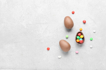 Composition with chocolate Easter eggs and candies on light background