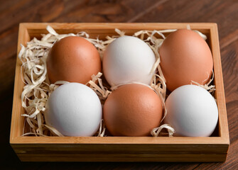 Box with fresh chicken eggs on wooden background