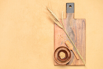 Wooden cutting board, bowls and wheat spikelets on beige background