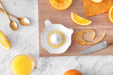 Ceramic juicer and oranges on light background