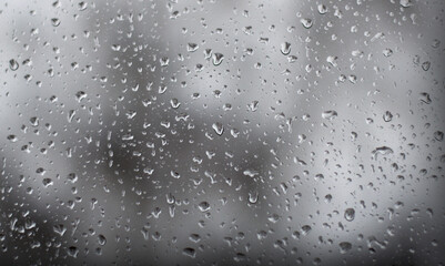 Closeup of waterdrops on the transparent glass after rain in grayscale