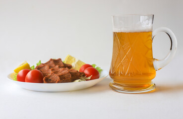 White background. Beer in a glass glass and cheesecake on a plate.