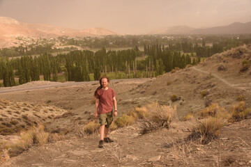 Young man standing against the background of vale and mountains. Argentina.