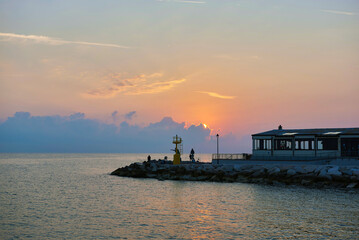 Obraz premium Adriatic sea, pier with people, sunset, waves and landscape. Rimini, Italy.