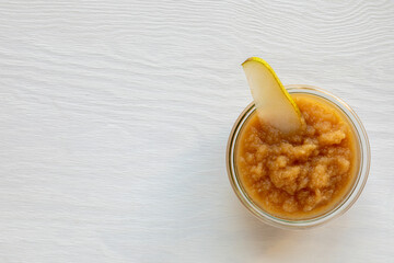 Bowl with pear fruit sauce on bright white wooden table. Healthy pear fruit snack dip, copy space.