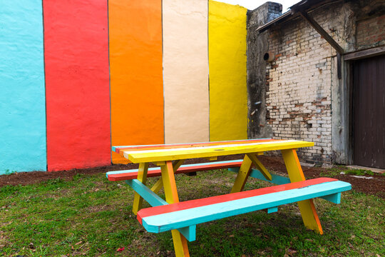 Colorful picnic table with benches on the grass against a painted wall