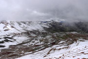 Uitzicht op Peru Vinicunca Rainbow Mountain bedekt met sneeuw onder de sombere hemel op een mistige dag