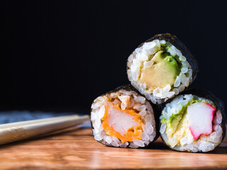 close-up of three pieces of sushi, maki piece, dark background 