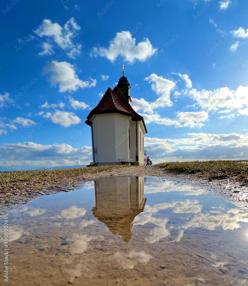 Poster beautiful view of an old chapel reflected on a water puddle on a cloudy sky background