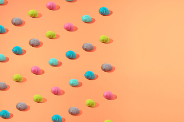 Pattern of colored snail houses against a orange background with copyspace. Minimal concept idea