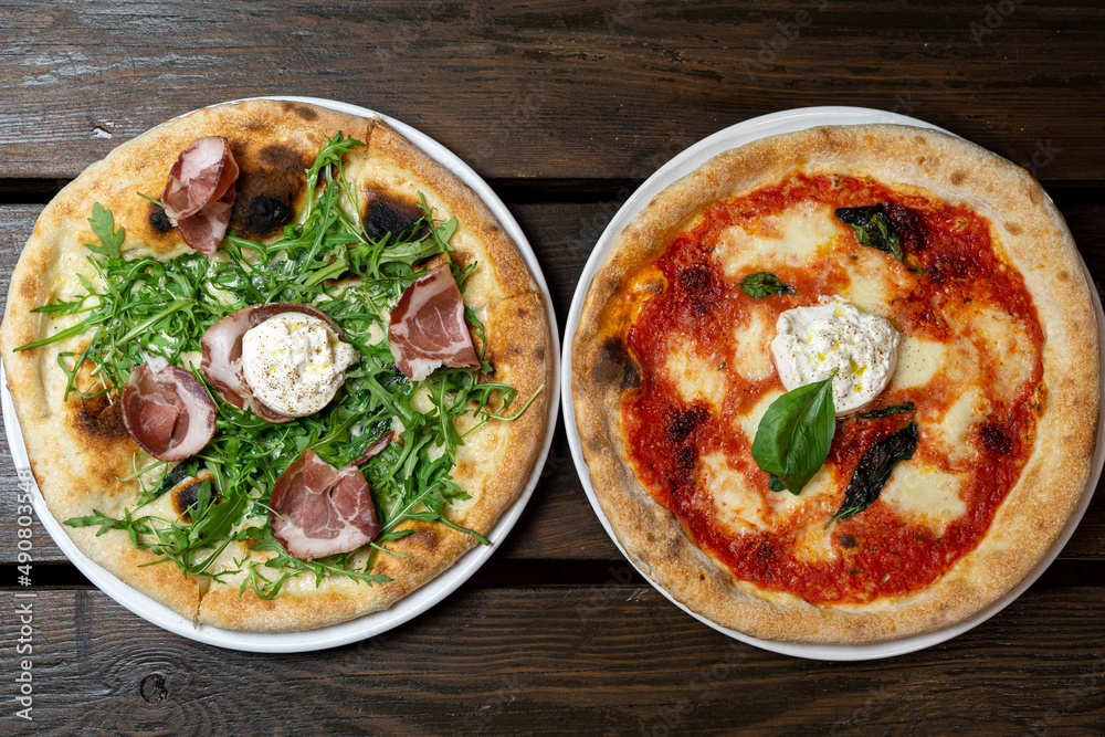 Wall mural Top view of tasty pizzas with cheese, beef and tomatoes on a wooden table