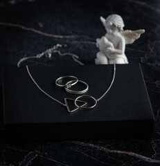 Silver necklace and rings on the dark marble
