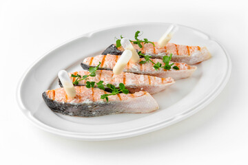 Grilled salmon fillet with sauce on a white plate. Banquet festive dishes. Gourmet restaurant menu. White background.
