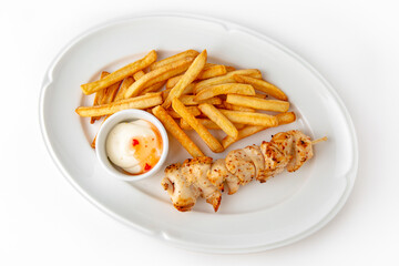 Chicken skewers with french fries and sauce on a white plate. Banquet festive dishes. Gourmet restaurant menu. White background.