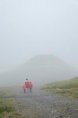 a young mother with her two children holding hands strolls through a mountain landscape on a foggy day