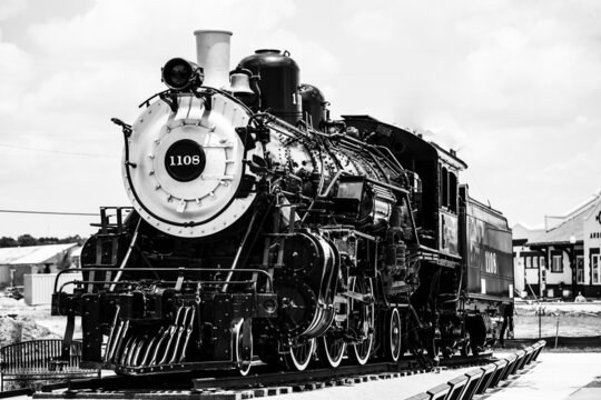 Grayscale shot of a train with steam engine on railroad