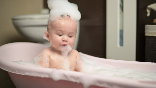 A little boy splashes in a bubble bath. child bathing in a bathtub