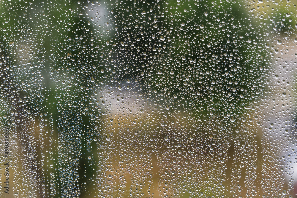 Sticker closeup of a window glass covered with raindrops with blurred view in the background