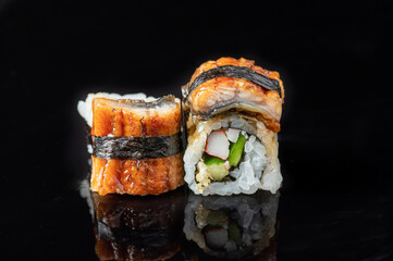 Tasty sushi rolls with crab sticks and avocado isolated on a black background