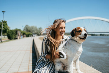 Beautiful young woman enjoying outdoors with her adorable adopted mixed breed dog. Bright sunny day.