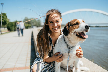 Beautiful young woman enjoying outdoors with her adorable adopted mixed breed dog. Bright sunny day.