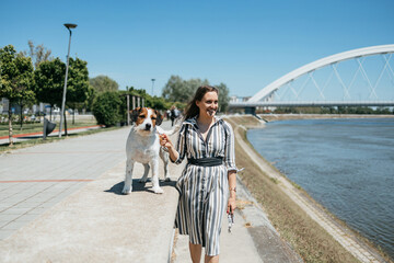Beautiful young woman enjoying outdoors with her adorable adopted mixed breed dog. Bright sunny day.