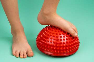 children's feet with a red balancer on a light green background, treatment and prevention of flat...
